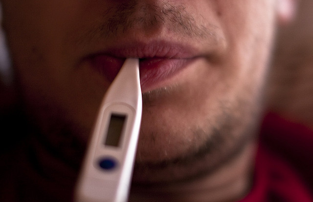 close up of a man face with en electronic thermometer